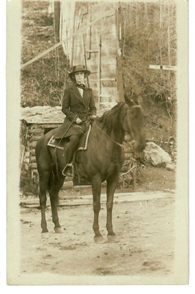 Item #31972 [Real Photo Postcard--Natty Woman Astride on Horseback in Front of Log Shed and...